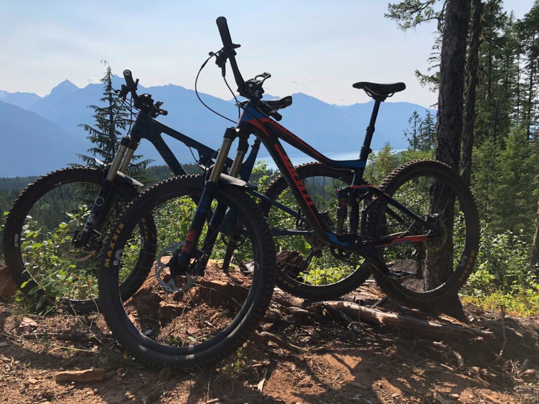 Two mountain bikes parked on the side of a hill.